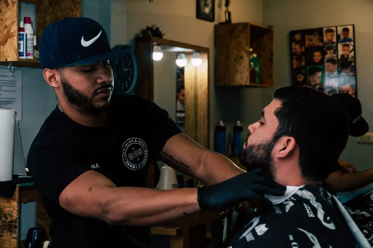Barbero trabajando sobre un cliente en el sillón